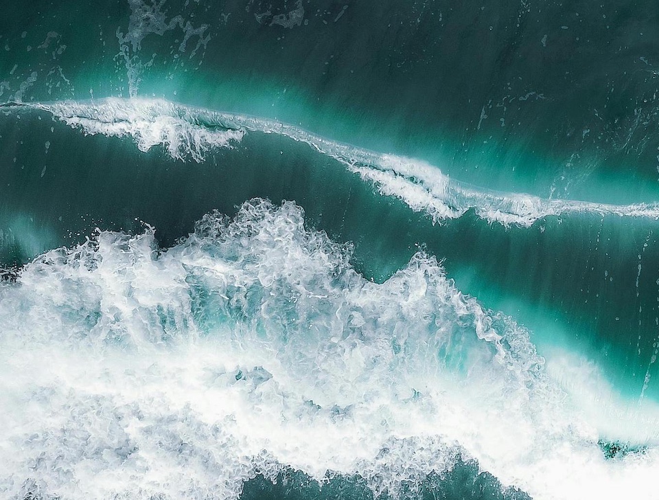 A birds eye view of a jade green sea with waves, photo by Pok Rie